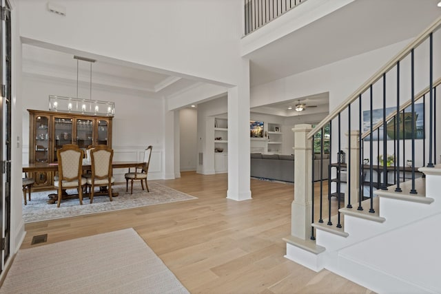 foyer featuring ceiling fan with notable chandelier, light hardwood / wood-style floors, and crown molding