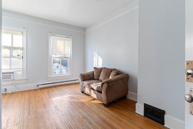 living area with hardwood / wood-style floors, a baseboard radiator, cooling unit, and crown molding