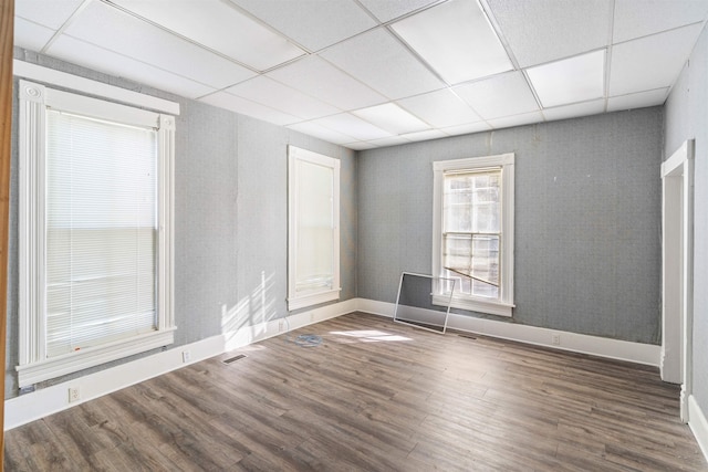 empty room with a paneled ceiling and dark wood-type flooring