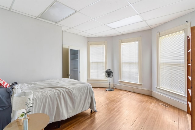 bedroom featuring multiple windows, a paneled ceiling, and wood-type flooring