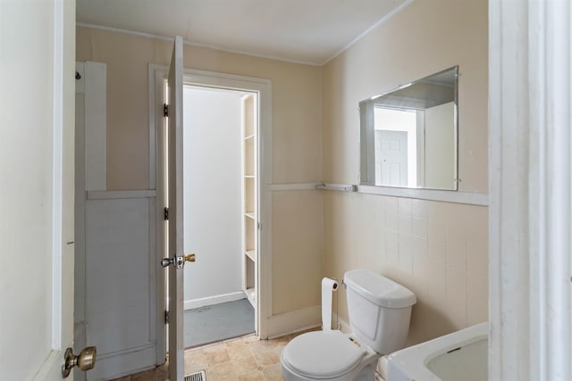 bathroom with toilet, tile walls, and sink