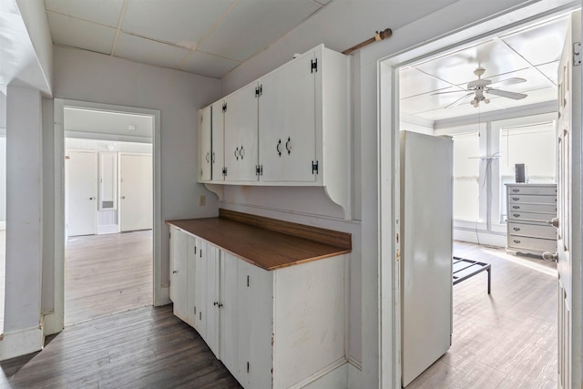 kitchen with wood-type flooring, a paneled ceiling, white cabinetry, and ceiling fan