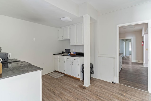 kitchen with a wood stove, white cabinetry, and light hardwood / wood-style flooring