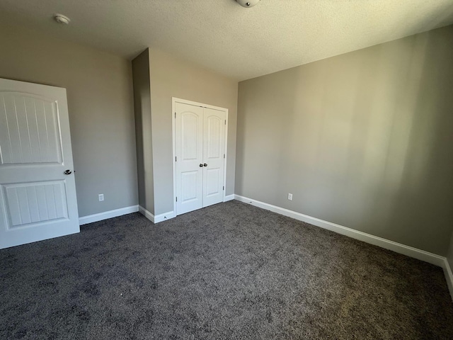 unfurnished bedroom featuring a closet, a textured ceiling, and dark colored carpet