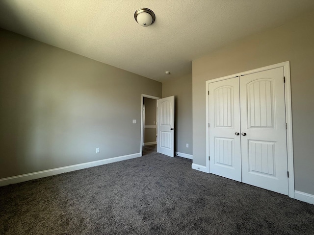 unfurnished bedroom with a textured ceiling, a closet, and dark colored carpet