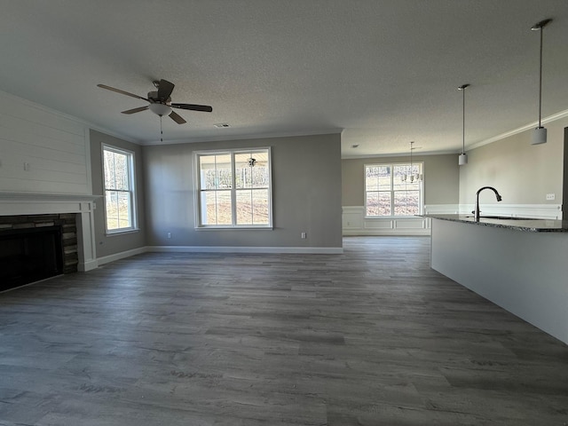 unfurnished living room featuring crown molding, sink, hardwood / wood-style floors, and a textured ceiling