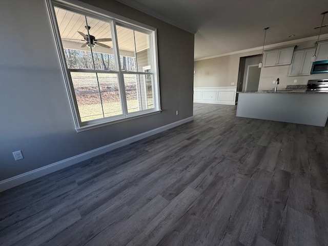 unfurnished living room featuring dark hardwood / wood-style flooring, sink, crown molding, and ceiling fan