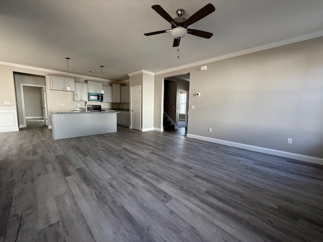 kitchen featuring hanging light fixtures, crown molding, a kitchen island with sink, and dark hardwood / wood-style flooring