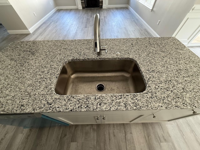 interior details featuring light stone countertops, sink, and hardwood / wood-style floors