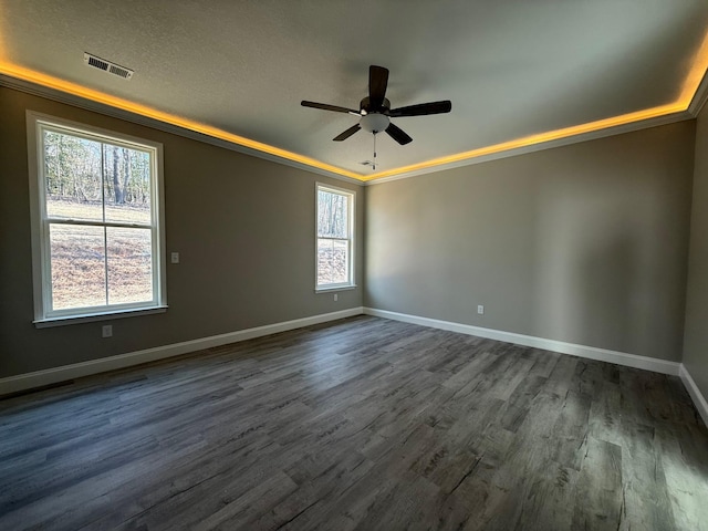 empty room with ceiling fan, dark hardwood / wood-style flooring, and a tray ceiling