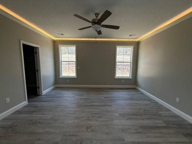 empty room featuring crown molding, ceiling fan, plenty of natural light, and hardwood / wood-style floors