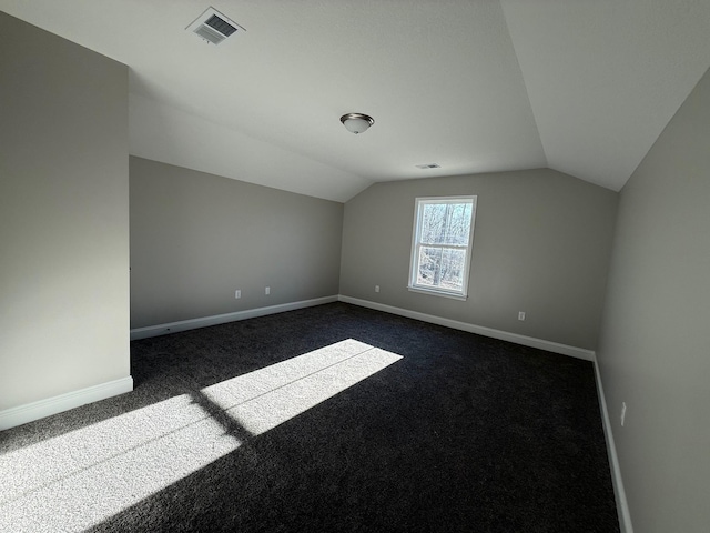 additional living space with lofted ceiling and dark colored carpet