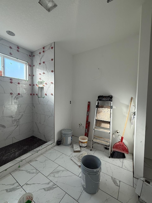 bathroom featuring a tile shower and a textured ceiling