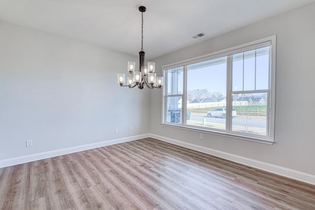 unfurnished room with light wood-type flooring and an inviting chandelier