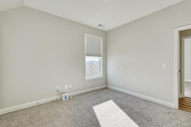 carpeted empty room featuring vaulted ceiling