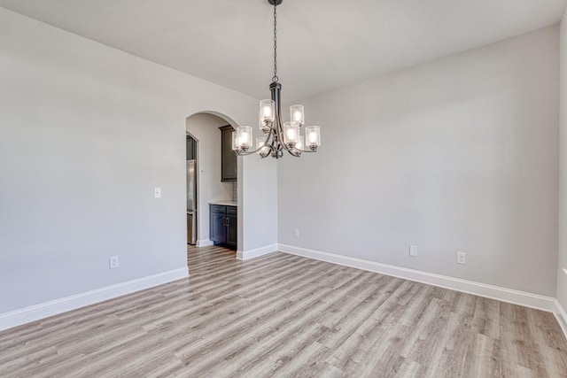 empty room with an inviting chandelier and light hardwood / wood-style flooring