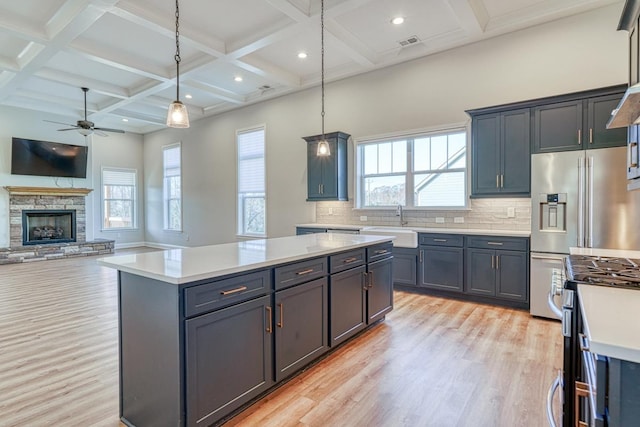 kitchen with backsplash, a stone fireplace, a center island, and decorative light fixtures