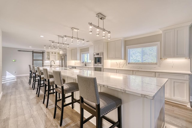 kitchen with a barn door, a spacious island, white cabinetry, and hanging light fixtures