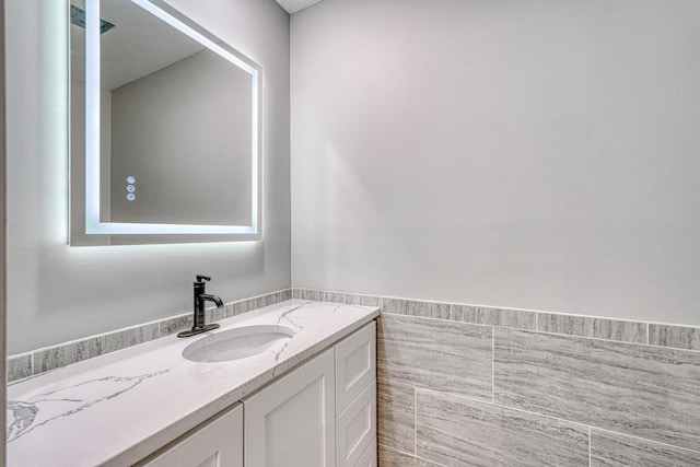 bathroom with vanity and tile walls