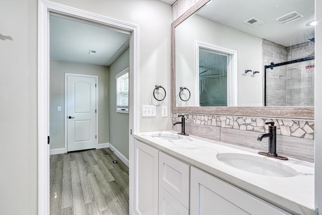 bathroom featuring backsplash, hardwood / wood-style floors, vanity, and walk in shower