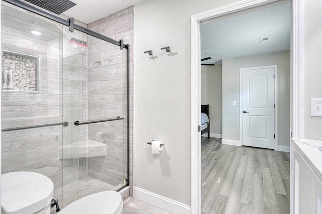 bathroom featuring wood-type flooring, vanity, toilet, and a shower with shower door