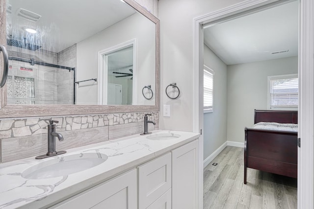 bathroom with hardwood / wood-style floors, vanity, decorative backsplash, and a shower with door