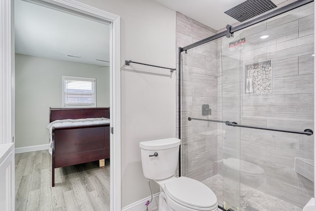 bathroom featuring toilet, a shower with door, and hardwood / wood-style flooring