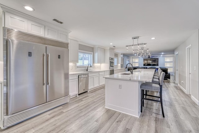 kitchen featuring sink, white cabinets, stainless steel appliances, and light hardwood / wood-style flooring