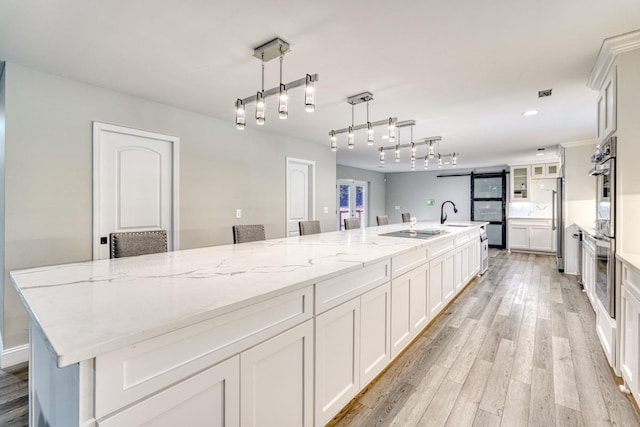 kitchen featuring white cabinets, pendant lighting, light hardwood / wood-style floors, and a spacious island