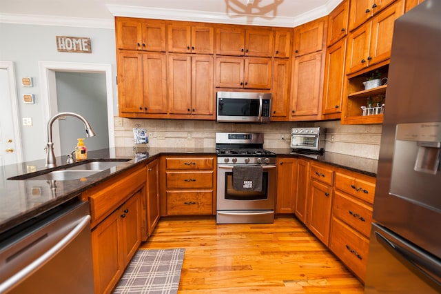 kitchen featuring sink, backsplash, crown molding, appliances with stainless steel finishes, and light wood-type flooring