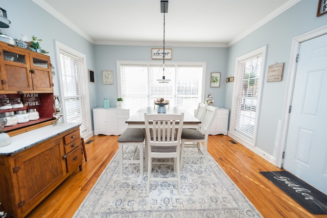 dining space featuring light hardwood / wood-style flooring, a wealth of natural light, and ornamental molding