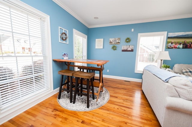 dining room with hardwood / wood-style flooring, a healthy amount of sunlight, and ornamental molding