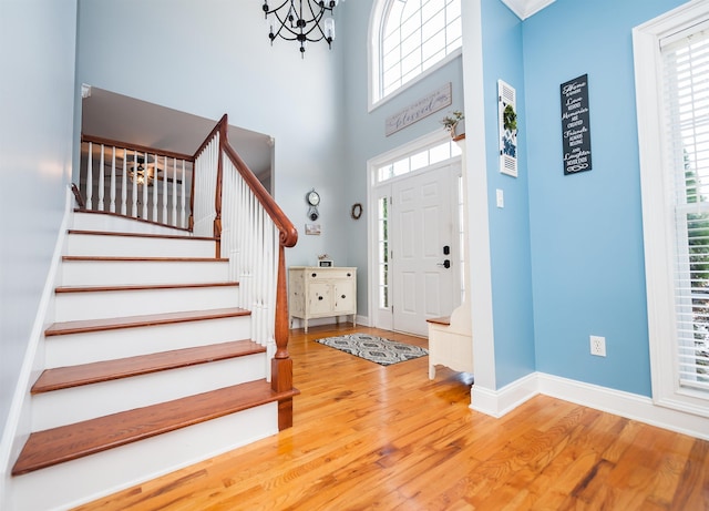 foyer featuring a towering ceiling, a chandelier, and hardwood / wood-style flooring