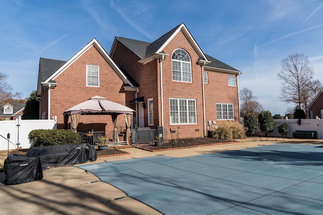 back of property with a gazebo, a covered pool, and a patio area