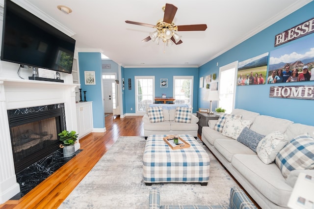 living room with ceiling fan, a fireplace, ornamental molding, and hardwood / wood-style flooring