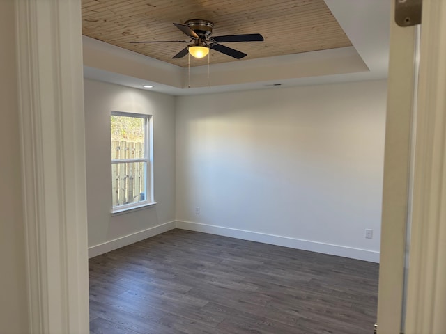 empty room featuring ceiling fan, wood ceiling, dark wood-type flooring, and a tray ceiling