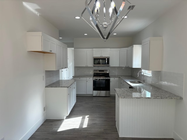 kitchen featuring appliances with stainless steel finishes, tasteful backsplash, sink, decorative light fixtures, and white cabinets