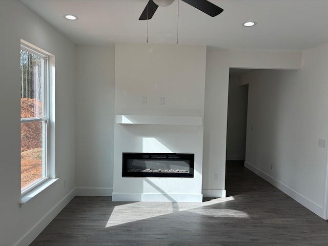 unfurnished living room featuring ceiling fan and dark hardwood / wood-style flooring