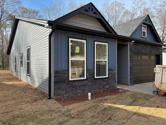 exterior space with a garage, stone siding, and board and batten siding