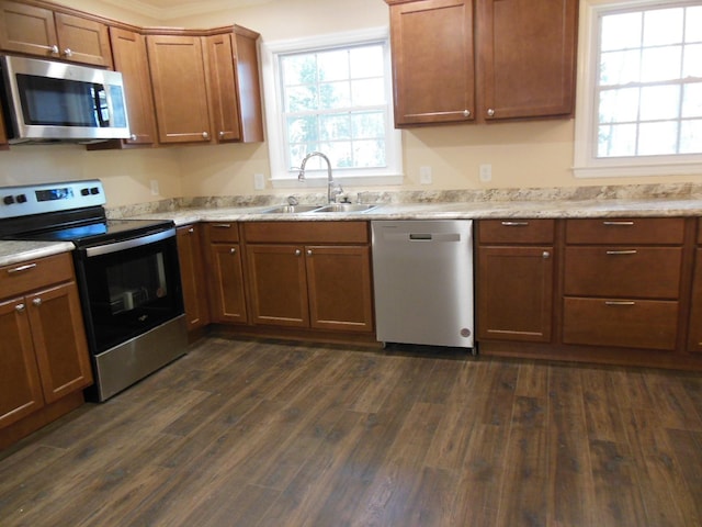 kitchen with light stone countertops, sink, dark wood-type flooring, and appliances with stainless steel finishes