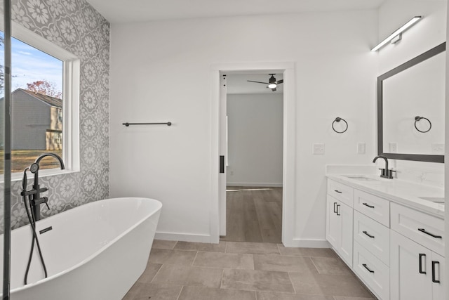 bathroom with a tub to relax in, ceiling fan, and vanity