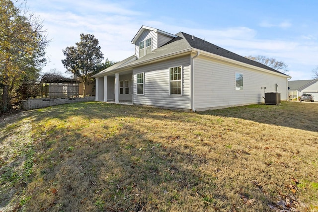 rear view of house with central air condition unit and a lawn