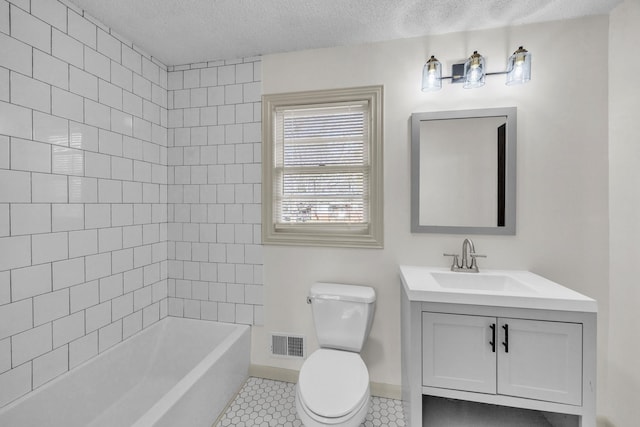 full bathroom with toilet, tiled shower / bath, a textured ceiling, vanity, and tile patterned flooring