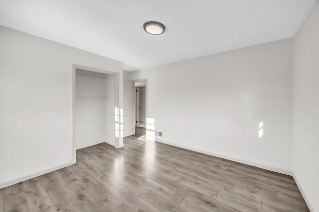 unfurnished bedroom featuring light hardwood / wood-style flooring and a closet