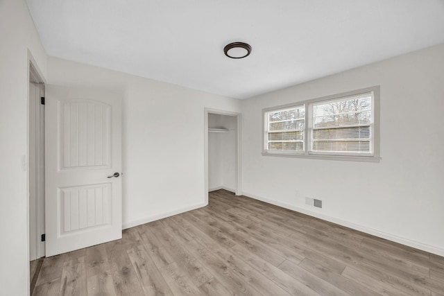 unfurnished bedroom with a closet and light wood-type flooring