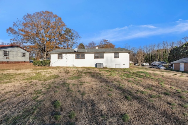 back of property featuring central AC unit and a lawn