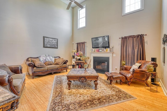 living room featuring ceiling fan, wood-type flooring, and a high ceiling