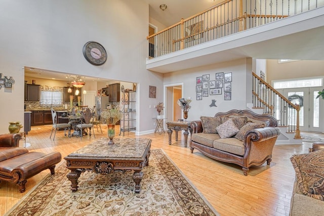 living room featuring light hardwood / wood-style floors, a high ceiling, and french doors