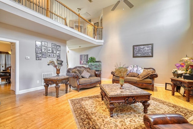 living room featuring a high ceiling, ceiling fan, and hardwood / wood-style floors