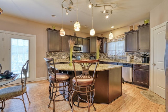 kitchen with a center island, dark brown cabinetry, stainless steel appliances, and hanging light fixtures